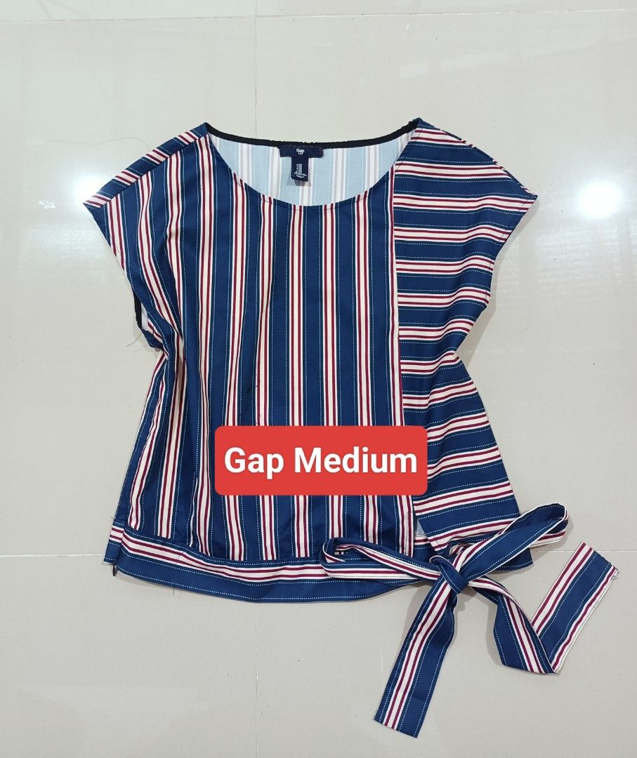 Gap Striped Tie-Side Blouse Medium (Category: Blouses) located in Angeles City. Submitted by leichen57360 (Listing ID 1465886098, Image 1). Description: - Brand: Gap - Size: Medium - Color: Blue - Design: Unique mix of vertical stripes on the front and horizontal stripes on the right side - Details: Rounded neckline, short sleeves, and a chic self-tie ribbon at the right side hem - Material: Smooth, comfortable fabric finish.