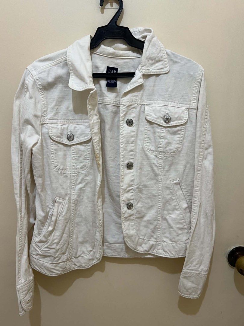 GAP White Denim Jacket (Category: Coats, Jackets and Outerwear) located in Manila. Submitted by longbondpaper (Listing ID 1465875621, Image 1). Description: - Brand: GAP - Style: Classic white denim jacket - Material: Textured white denim fabric - Closure: Button-down front with metal hardware - Pockets: Two chest flap pockets and two side slip pockets - Details: Structured collar and long sleeves with button cuffs - Fit/Use: Great casual staple 