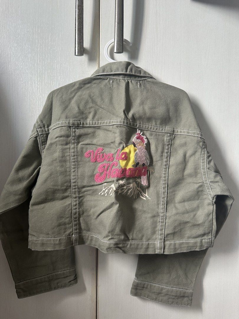 Gingersnaps Green Cropped Jacket Size 4 (Category: Babies & Kids Fashion) located in Quezon City. Submitted by maricrisdiokno (Listing ID 1465828199, Image 3). Description: - Brand: Gingersnaps - Size: 4 - Color: Green with white contrast stitching - Material: Sturdy cotton fabric - Features: Button-up front, collar, and chest pockets - Back Details: Cute embroidered parrot graphic and pink text accent - Condition: Great statement piece for kids.