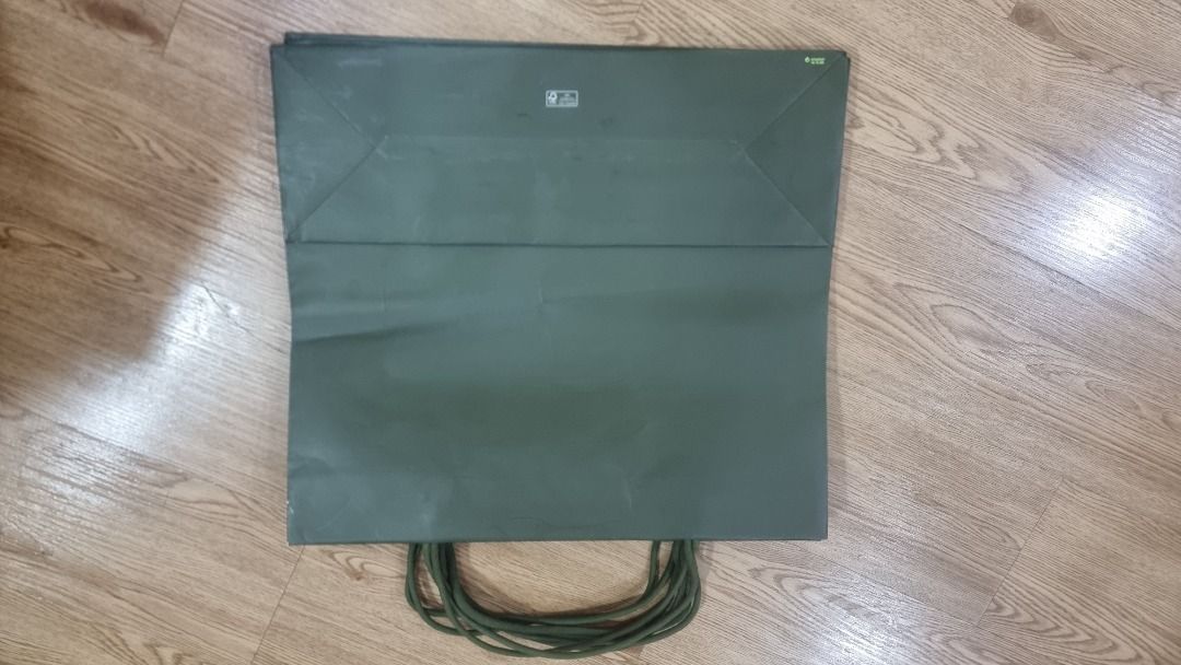 Green Paper Bag with Handles (Category: Tote Bags) located in Paranaque City. Submitted by olxph_668280920 (Listing ID 1465872729, Image 2). Description: - Color: Dark green with a simple solid design - Material: Sturdy paper with dark green rope handles - Storage: Flat-folded design with fold creases across the middle for easy storage - Usage: Ideal for gifting or carrying lightweight items.