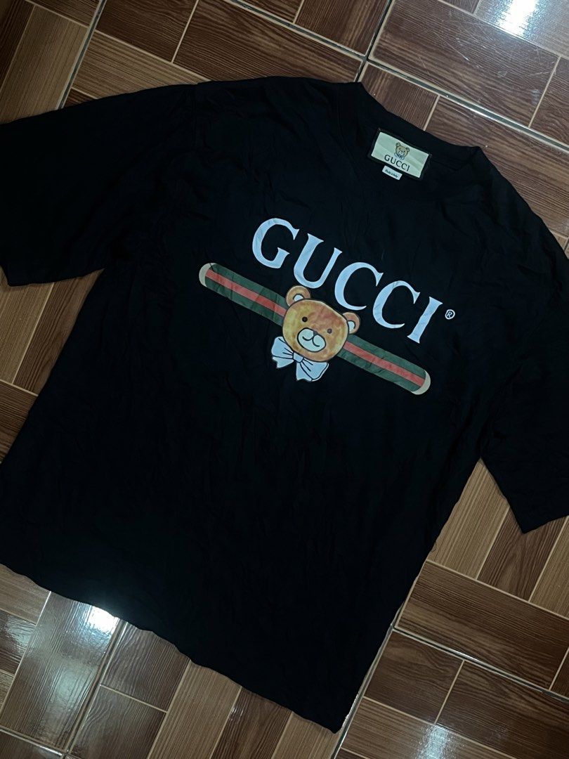 Gucci Black Bear Graphic T-Shirt (Category: Tshirts & Polo Shirts ) located in Manila. Submitted by cycy16_2004 (Listing ID 1465765908, Image 1). Description: - Brand: Gucci - Color: Black - Material: 100% Cotton - Design: Large playful bear graphic over signature green and red stripe on front, pink circular logo patch on back - Details: Short sleeves, round neckline, Made in Italy label, and interior care tags attached - Condition: Excellent cas