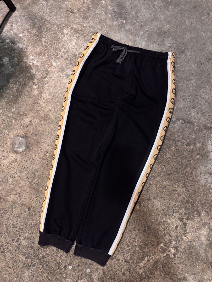 Gucci Black Sweatpants with Interlocking G Side Stripes (Category: Joggers) located in Pasig City. Submitted by dripthrift1600 (Listing ID 1465949464, Image 1). Description: - Authentic Gucci sweatpants in classic black fleece - Elastic waistband with adjustable drawstring closure - Signature tan side stripes with iconic interlocking G monogram and white piping - Comfortable cuffed ankles and casual fit - Premium clean cotton blend material - Mad