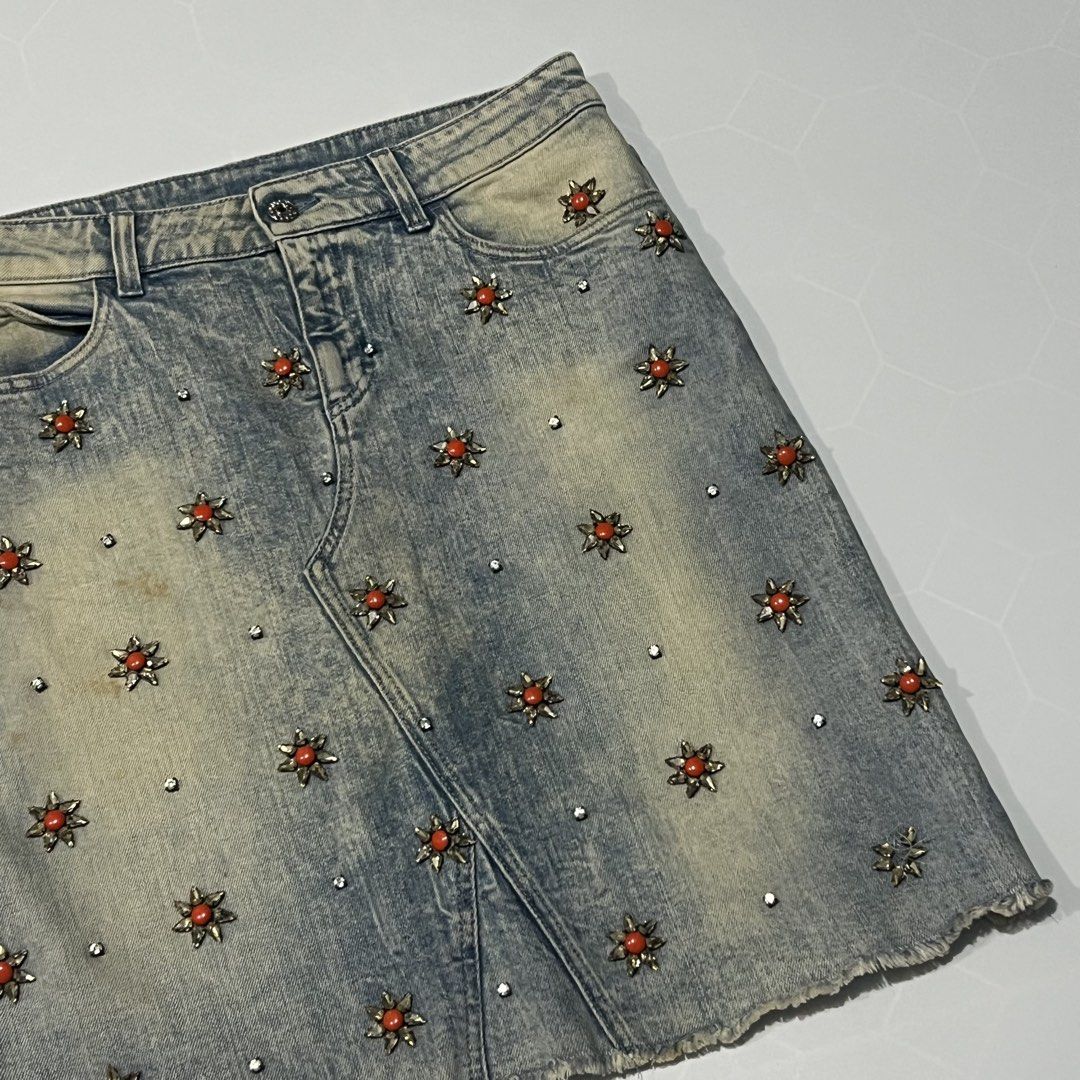 Gucci Embellished Denim Skirt (Category: Skirts) located in Caloocan City. Submitted by lostarchive_55 (Listing ID 1465916087, Image 2). Description: - Brand: Gucci - Style: Mid-length denim skirt with front seam detail and classic 5-pocket design - Wash: Blue acid wash - Size: 42 (Made in Italy) - Details: Covered in metallic flower studs with orange center beads and rhinestone crystals - Finish: Raw hem bottom with branded hardware on button an