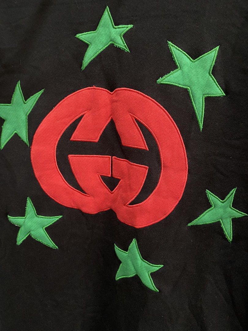 Gucci Interlocking G Star Hoodie Black (Category: Hoodies) located in Manila. Submitted by mokshit_thrift_9 (Listing ID 1465815137, Image 2). Description: - Brand: Gucci - Color: Black with red and green details - Design: Large red Interlocking G logo on chest surrounded by green embroidered stars - Features: Drawstring hood, front pouch pocket - Material: 100% Cotton - Authenticity details: Blue and red Gucci neck label, Made in Italy tag - Cond