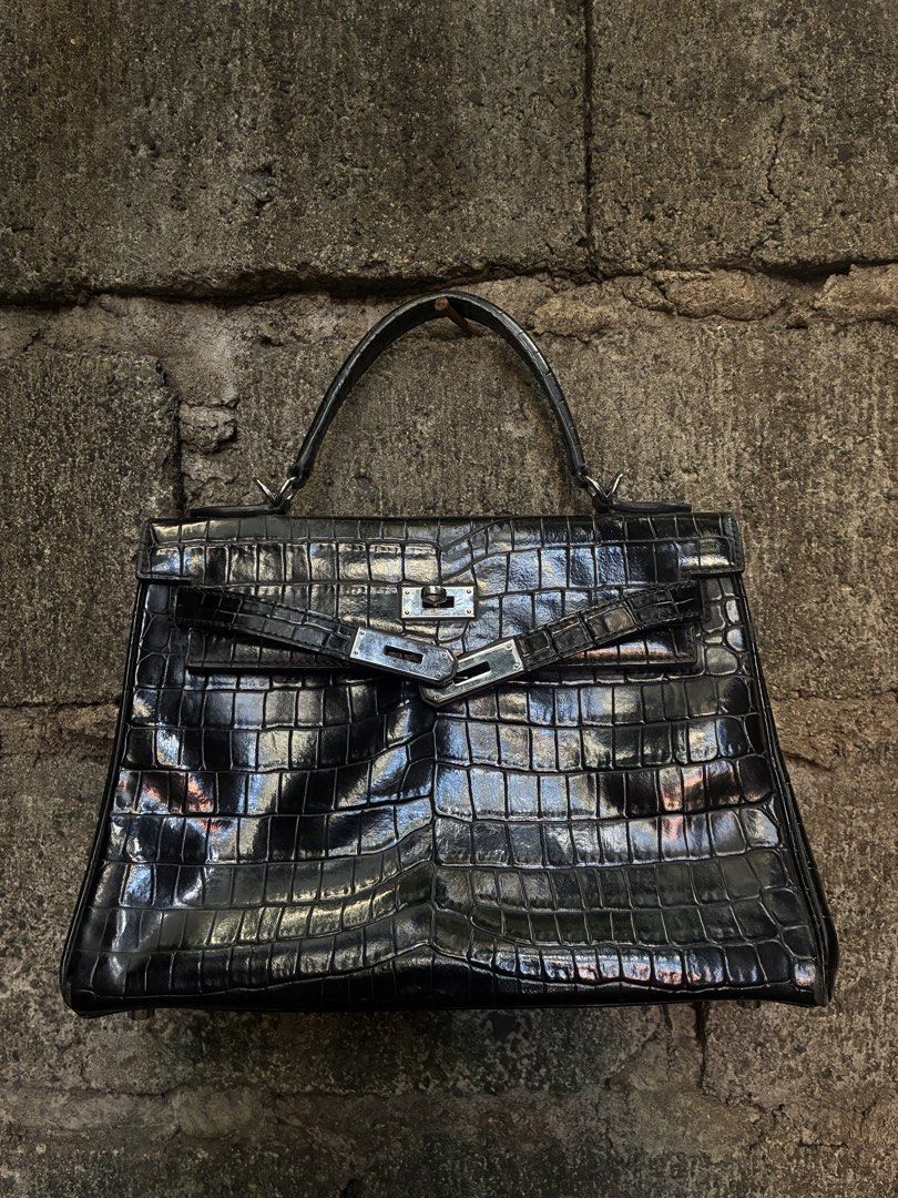 Hermes Kelly 28 Black Crocodile Handbag (Category: Luxury Bags & Wallets) located in Manila. Submitted by assortedgoodsv3 (Listing ID 1465764488, Image 1). Description: Hermes Kelly bag in black crocodile skin. Silver hardware closure, Hermes Paris engraving on the metal plate. Stamp visible on the strap. Interior lined in black leather with zipper pocket. Structured top handle design..