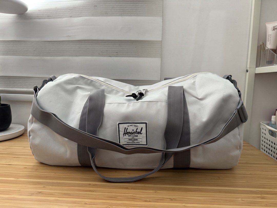 Herschel Duffel Bag (Category: Cross-body Bags) located in Makati City. Submitted by the.archives (Listing ID 1465864809, Image 1). Description: - Authentic Herschel duffel bag in versatile light grey canvas - Spacious main compartment ideal for gym gear, weekend trips, or daily travel - Durable grey carry handles and adjustable shoulder strap with sturdy clips - Secure dual zipper closure with signature branded and leather pulls - Classic Hersch