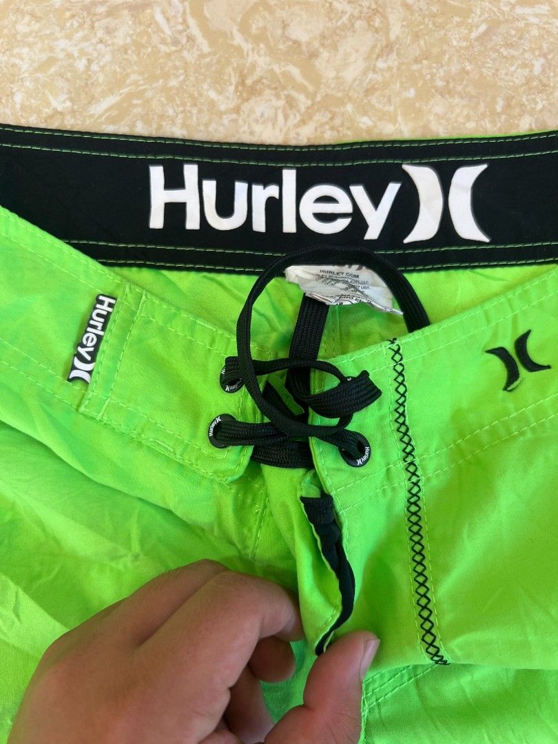 Hurley Neon Green Boardshorts (Category: Swim Trunks & Board Shorts) located in Bacoor. Submitted by davealvare39194 (Listing ID 1465858653, Image 3). Description: - Brand: Hurley - Color: Bright neon green with black details - Material: Lightweight surf fabric - Features: Contrast stitching, right leg flap pocket with logo, black drawstring with reinforced eyelets - Waistband: Wide black waistband with large white Hurley branding inside - Condit