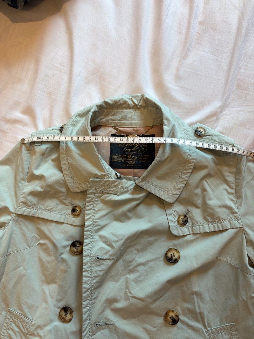 ijiit Light Green Trench Coat Jacket （分類：外套及戶外衣服）位於 Hong Kong。 由 orcus_lux 提交（商品編號 1465842299，圖片 5）。簡介： Light green trench coat from Diary Original ijüt. Double-breasted front with tortoiseshell buttons, epaulets on shoulders, and adjustable sleeve cuffs. Back storm flap with single button. Beige lining inside plus chain locker loop at the collar. Pit-to-pit measurement around 38 cm based on tape measure. Solid everyday outerwear piece for transi