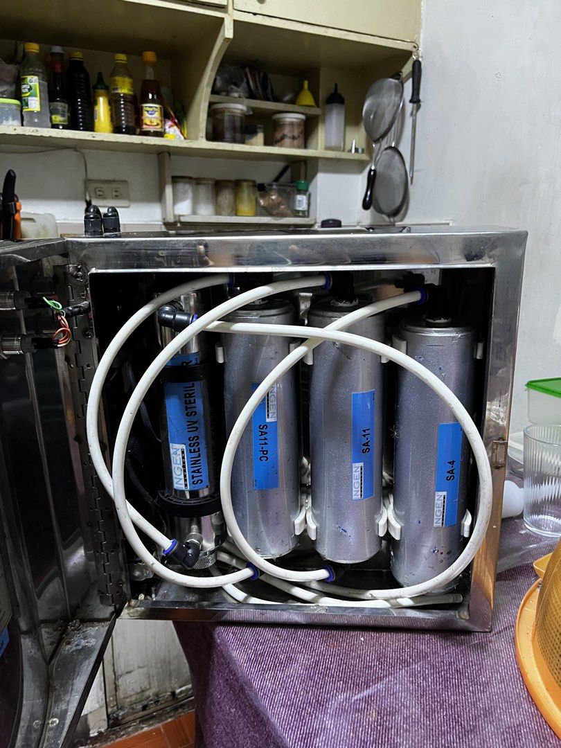 Ingen Stainless Steel Water Purifier System (Category: Water Purifiers & Dispensers) located in Manila. Submitted by samsison6814720 (Listing ID 1465798101, Image 2). Description: - Brand: Ingen stainless steel water purifier setup - Housing: Polished metal cabinet with hinged door (protective plastic film still on parts) - Filtration: Multiple internal cylinder filters (SA-4, SA-11, SA11-PC) - Sterilization: Includes stainless UV sterilizer tube