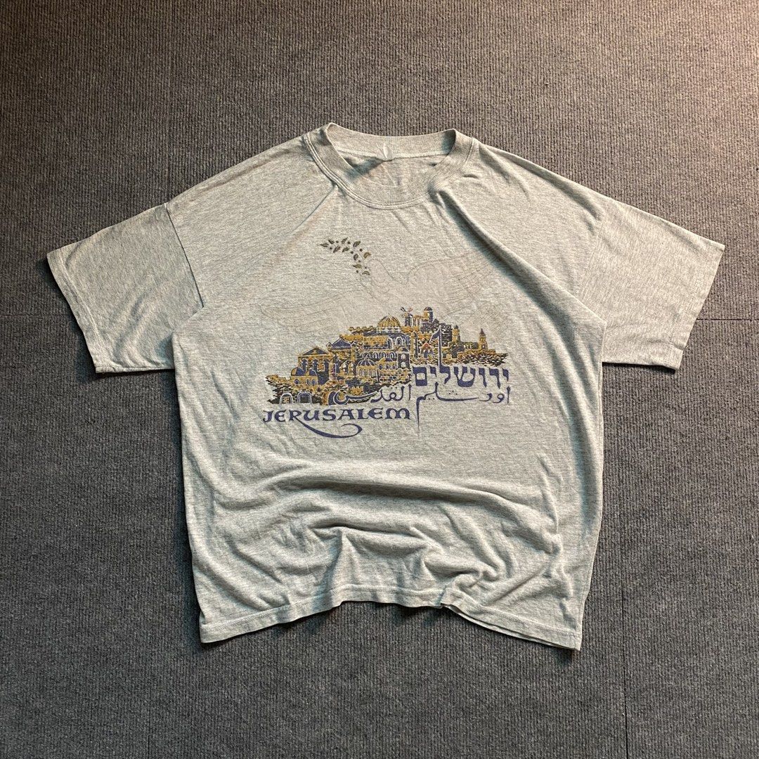 Jerusalem Graphic Tee Grey Short Sleeve Shirt (Category: Shirts) located in Malaybalay. Submitted by mat.loots (Listing ID 1465873810, Image 1). Description: - Color: Grey - Design: Jerusalem city skyline with English, Hebrew, and Arabic text, and an olive branch motif - Fit: Relaxed fit with a classic crew neck - Material/Style: Short sleeve t-shirt, great for casual everyday wear.