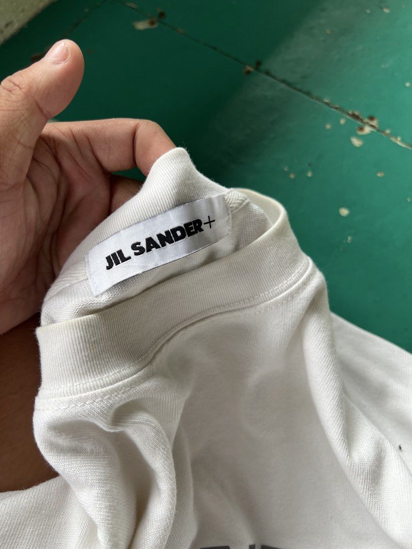 Jil Sander+ Arc'teryx White T-Shirt (Category: Shirts) located in Manila. Submitted by vastriver-12e2c3 (Listing ID 1465892954, Image 3). Description: - Authentic Jil Sander Plus x Arc'teryx collaboration - Color: Crisp white - Size Small to Medium - 22x27 Dimes - Material: 100% premium cotton, made in Italy - Design: Bold black chest lettering with bright orange sleeve logo - Details: Signature orange plus tag near the hem - Fit: Classic crew ne