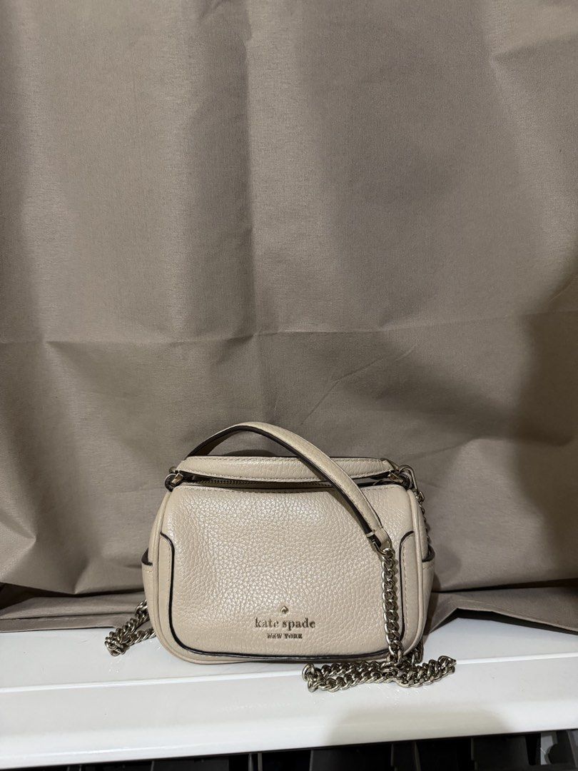 Kate Spade Smoosh Micro Crossbody Bag (Category: Cross-body Bags) located in Quezon City. Submitted by declutterbycy (Listing ID 1465832990, Image 3). Description: - Brand: Kate Spade New York - Material: Premium beige pebbled leather - Hardware: Gold-tone with engraved zipper pull - Straps: Top handle and detachable chain strap - Closure: Zip-top - Interior: Fabric-lined with a convenient slip pocket - Condition: Excellent / Well-maintained.