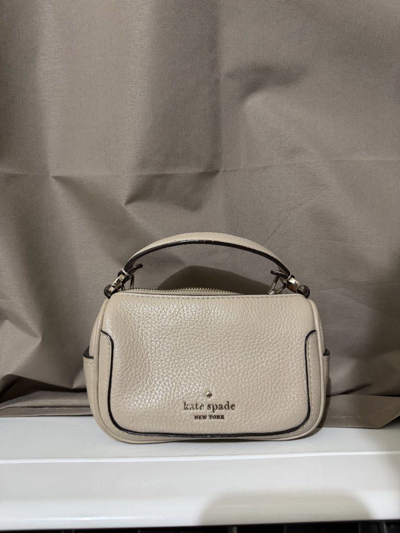Kate Spade Smoosh Micro Crossbody Bag (Category: Cross-body Bags) located in Quezon City. Submitted by declutterbycy (Listing ID 1465832990, Image 1). Description: - Brand: Kate Spade New York - Material: Premium beige pebbled leather - Hardware: Gold-tone with engraved zipper pull - Straps: Top handle and detachable chain strap - Closure: Zip-top - Interior: Fabric-lined with a convenient slip pocket - Condition: Excellent / Well-maintained.