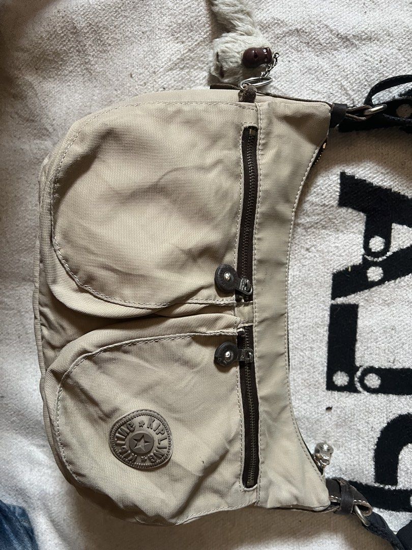 Kipling beige nylon shoulder bag with monkey keychain (Category: Shoulder Bags) located in Cagayan de Oro. Submitted by nelsondel21723 (Listing ID 1465818306, Image 2). Description: - Brand: Kipling - Color: Neutral beige - Material: Durable nylon - Features: Dual exterior front zipper pockets and a spacious main zip compartment - Strap: Adjustable black strap for versatile wear - Extra: Includes the classic fuzzy monkey keychain - Condition: Exc