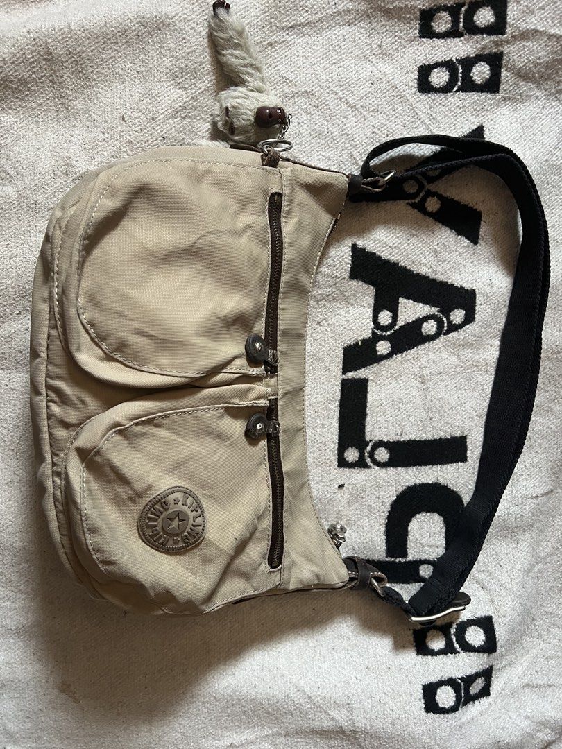 Kipling beige nylon shoulder bag with monkey keychain (Category: Shoulder Bags) located in Cagayan de Oro. Submitted by nelsondel21723 (Listing ID 1465818306, Image 1). Description: - Brand: Kipling - Color: Neutral beige - Material: Durable nylon - Features: Dual exterior front zipper pockets and a spacious main zip compartment - Strap: Adjustable black strap for versatile wear - Extra: Includes the classic fuzzy monkey keychain - Condition: Exc