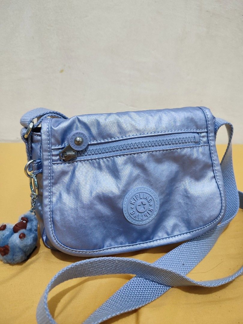 Kipling Light Blue Crossbody Bag with Monkey Keychain (Category: Cross-body Bags) located in Bacoor. Submitted by almfl (Listing ID 1465901131, Image 1). Description: - Authentic Kipling crossbody bag in light blue nylon - Flap closure with front zippered pocket - Interior includes branded Light label and zippered compartment - Adjustable strap for comfortable wear - Comes with signature furry blue monkey keychain - Clean inside and out, used onl