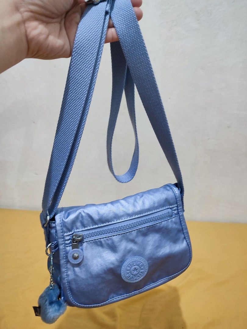 Kipling Light Blue Crossbody Bag with Monkey Keychain (Category: Cross-body Bags) located in Bacoor. Submitted by almfl (Listing ID 1465901131, Image 3). Description: - Authentic Kipling crossbody bag in light blue nylon - Flap closure with front zippered pocket - Interior includes branded Light label and zippered compartment - Adjustable strap for comfortable wear - Comes with signature furry blue monkey keychain - Clean inside and out, used onl