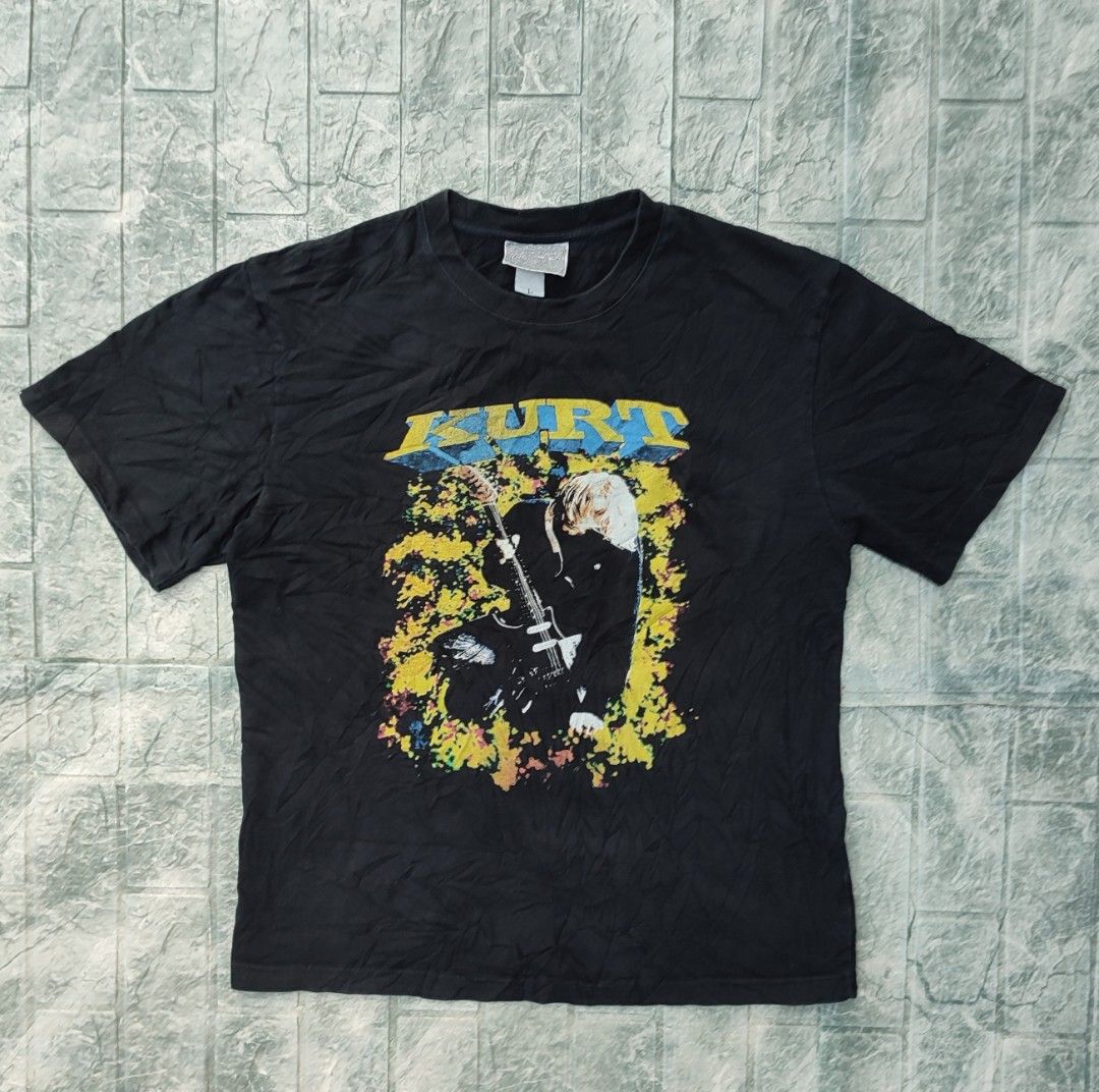 Kurt Cobain Nirvana Graphic Black T-Shirt (Category: Tshirts & Polo Shirts ) located in Bayambang. Submitted by mon10192816 (Listing ID 1465879452, Image 1). Description: - Width 22 - Length 27.5 - Brand/Tag: Ice Valley - Size: Large - Color: Black - Material: Soft cotton, regular fit - Design: Kurt Cobain guitar graphic with yellow splatter on the front; large close-up portrait with blue eyes and name on the back - Style: Short sleeves, grunge/r