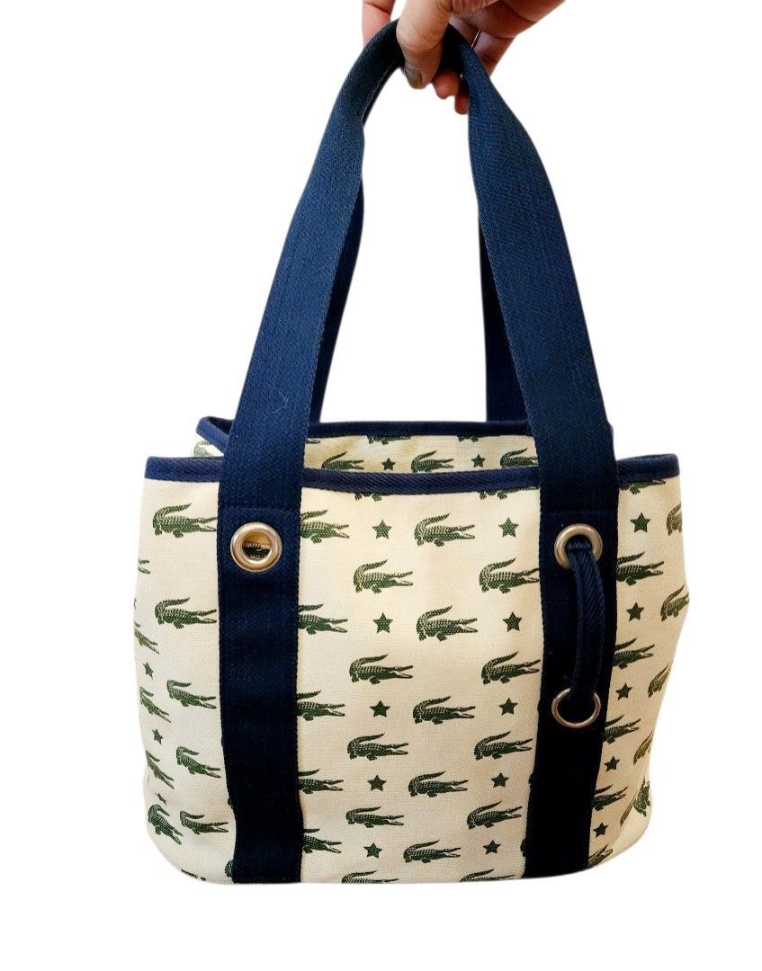 Lacoste All-Over Crocodile Monogram Canvas Tote Bag (Category: Tote Bags) located in Caloocan City. Submitted by grandhorse-c5575b (Listing ID 1465951828, Image 1). Description: - Material: Sturdy cream canvas with dark blue trim - Design: All-over green crocodile and star print - Features: Durable fabric handles with metal grommets - Capacity: Roomy interior, perfect for daily essentials - Condition: Brand new.