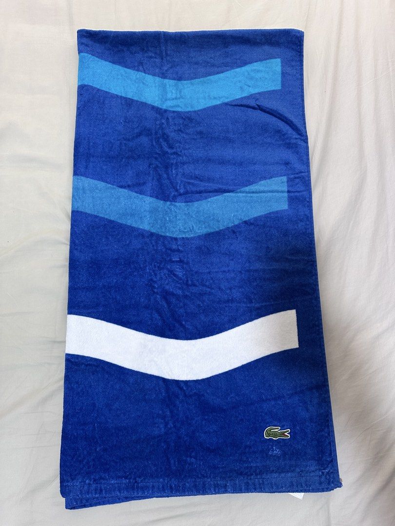 Lacoste Blue Beach Towel (Category: Bedding & Towels) located in Quezon City. Submitted by aussomefinds (Listing ID 1465852056, Image 1). Description: - Brand: Lacoste - Design: Striped wave patterns in light blue and white with classic embroidered crocodile logo - Size: Approx. 36 inches x 69 inches - Texture: Soft and plush - Condition: Brand new / Excellent (as seen in photos).