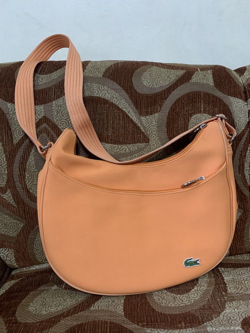 Lacoste Peach Crossbody Shoulder Bag (Category: Cross-body Bags) located in Las Pinas. Submitted by vanethneth (Listing ID 1465882611, Image 1). Description: - Peach Lacoste crossbody bag with a trendy curved crescent shape - Adjustable strap for a comfortable, customized fit - Convenient front zipped pocket and secure main zip closure - Stylish green and white striped fabric lining with an internal zip pocket - Accented with classic silver-toned