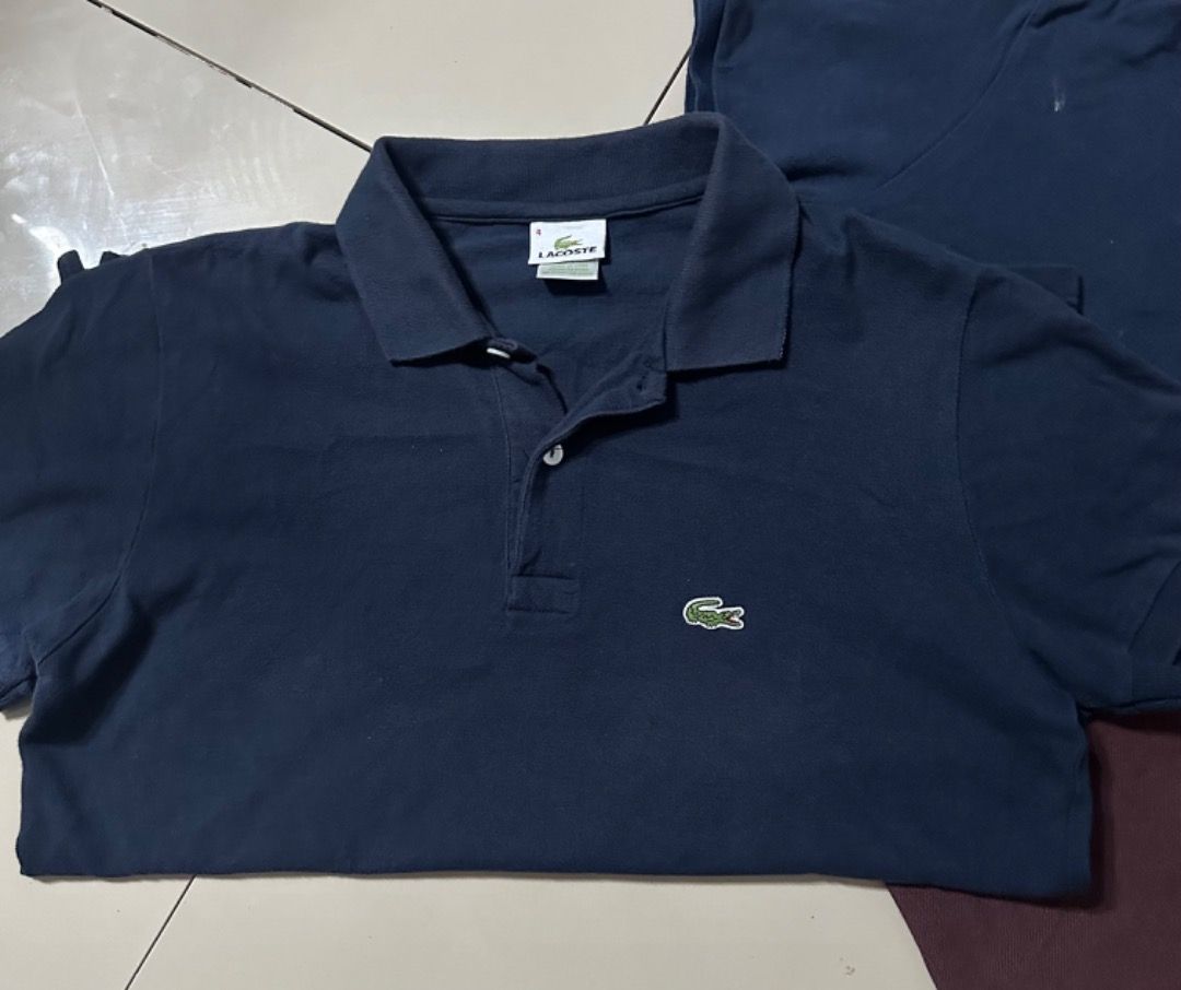 Lacoste Polo Shirts Bundle of 3 (Category: Tshirts & Polo Shirts ) located in Davao. Submitted by ithrift2k24 (Listing ID 1465904422, Image 3). Description: Bundle of three Lacoste polo shirts. Includes two navy blue and one dark maroon/brown. Classic fit with signature embroidered crocodile logo on the chest. Collared neck with two-button placket. Standard short sleeve style. All three pieces included in this set. Great casual staples for everyd