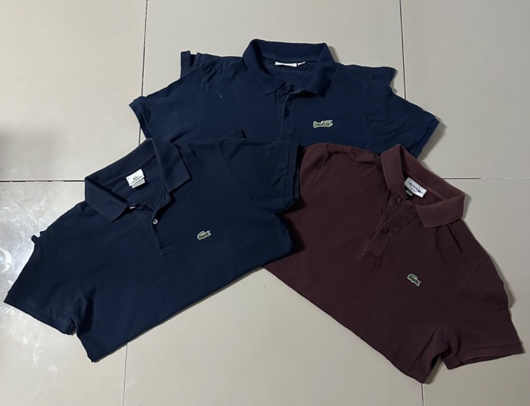 Lacoste Polo Shirts Bundle of 3 (Category: Tshirts & Polo Shirts ) located in Davao. Submitted by ithrift2k24 (Listing ID 1465904422, Image 2). Description: Bundle of three Lacoste polo shirts. Includes two navy blue and one dark maroon/brown. Classic fit with signature embroidered crocodile logo on the chest. Collared neck with two-button placket. Standard short sleeve style. All three pieces included in this set. Great casual staples for everyd