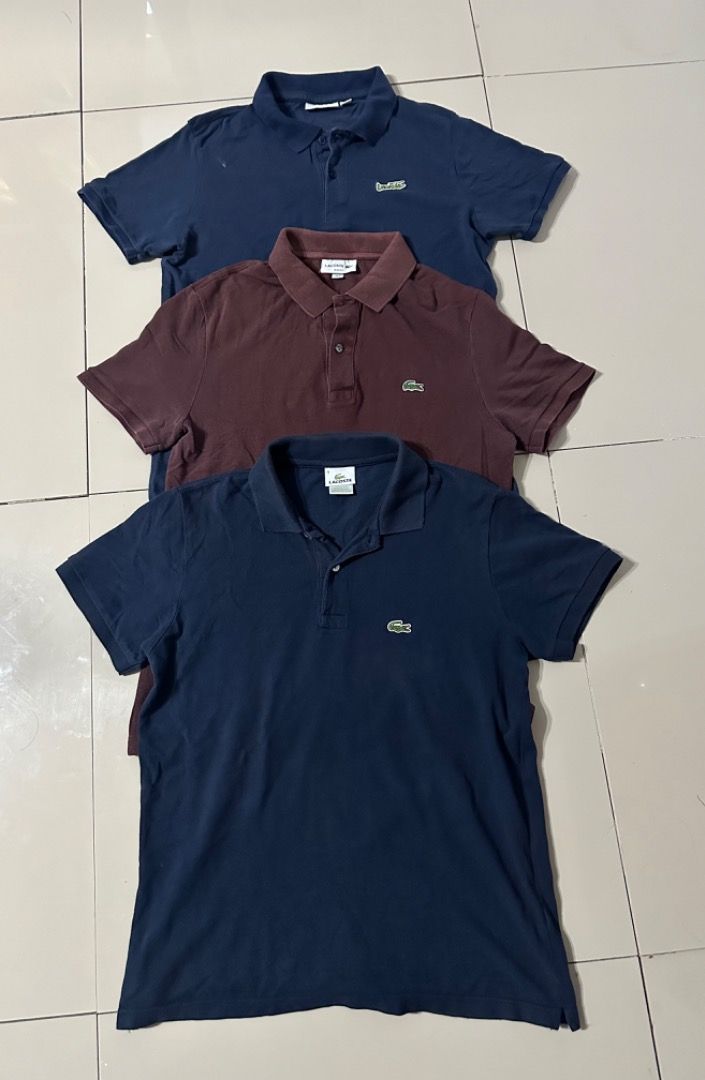 Lacoste Polo Shirts Bundle of 3 (Category: Tshirts & Polo Shirts ) located in Davao. Submitted by ithrift2k24 (Listing ID 1465904422, Image 1). Description: Bundle of three Lacoste polo shirts. Includes two navy blue and one dark maroon/brown. Classic fit with signature embroidered crocodile logo on the chest. Collared neck with two-button placket. Standard short sleeve style. All three pieces included in this set. Great casual staples for everyd