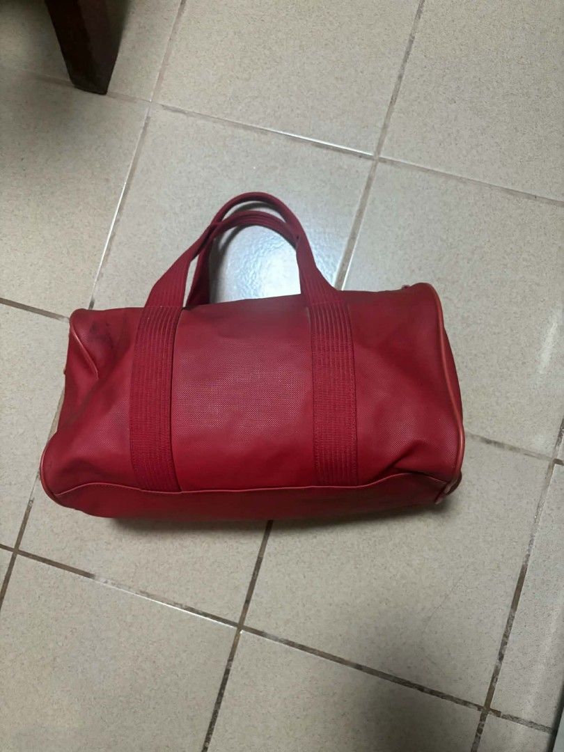 Lacoste Red Barrel Duffel Bag (Category: Sling Bags) located in Caloocan City. Submitted by joshuadyogi0122 (Listing ID 1465778631, Image 3). Description: - Brand: Lacoste - Color: Bright red with iconic embossed crocodile logo - Material: Textured outer finish with light canvas lining - Features: Sturdy webbed handles, chunky zip closure, and interior slip pockets - Size & Use: Roomy interior ideal for gym sessions, daily carry, or short getaway