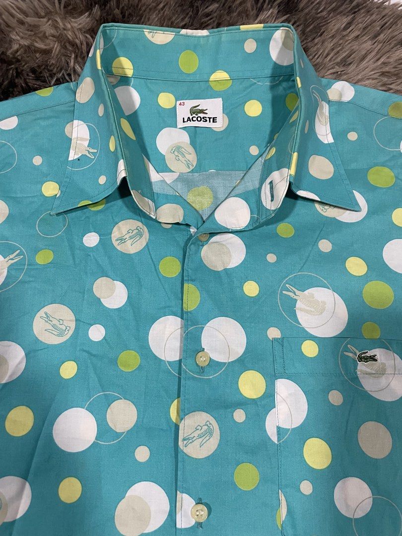 Lacoste Turquoise All Overprint Polo (Category: Formal Shirts) located in Calapan. Submitted by lucasthrifts (Listing ID 1465922343, Image 3). Description: - Brand: Lacoste - Size: Large( Approx. 23 inches pit-to-pit) - Color/Design: Turquoise with white & lime green polka dots and faint alligator graphics - Details: Short sleeve, button-up, pointed collar, single chest pocket with embroidered green crocodile logo - Material: Lightweight fabric w