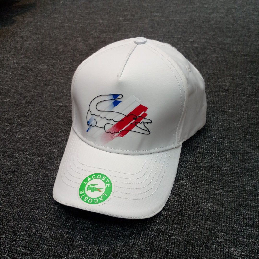 Lacoste White Baseball Cap with Graphic Crocodile Logo (Category: Caps & Hats) located in Manila. Submitted by pablopresk0. (Listing ID 1465835044, Image 1). Description: - Brand: Lacoste - Color: Clean white with blue and red graphic stripes - Logo: Outline crocodile with graphic background - Fit: Adjustable strap at the back with a secure metal clasp - Details: Branded Lacoste tape on interior seams and original round sticker on the brim - Cond
