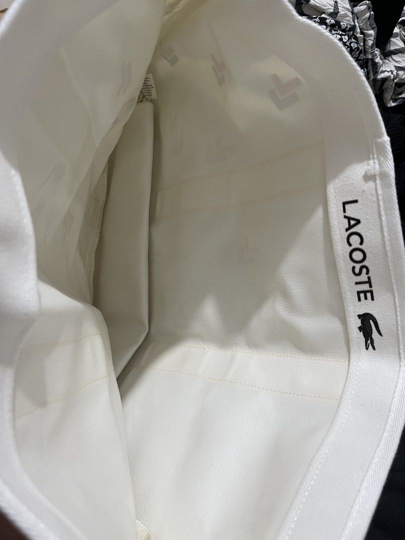 Lacoste White Canvas Tote Bag with Graphic Pattern (Category: Tote Bags) located in Paranaque City. Submitted by twinmanila (Listing ID 1465900065, Image 2). Description: - Lacoste canvas tote bag in white - Features a playful red and blue crocodile graphic print - Sturdy white handles with a structured flat bottom - Roomy interior with branded inner lining and slip pocket - Clean fabric all around, great for everyday use.