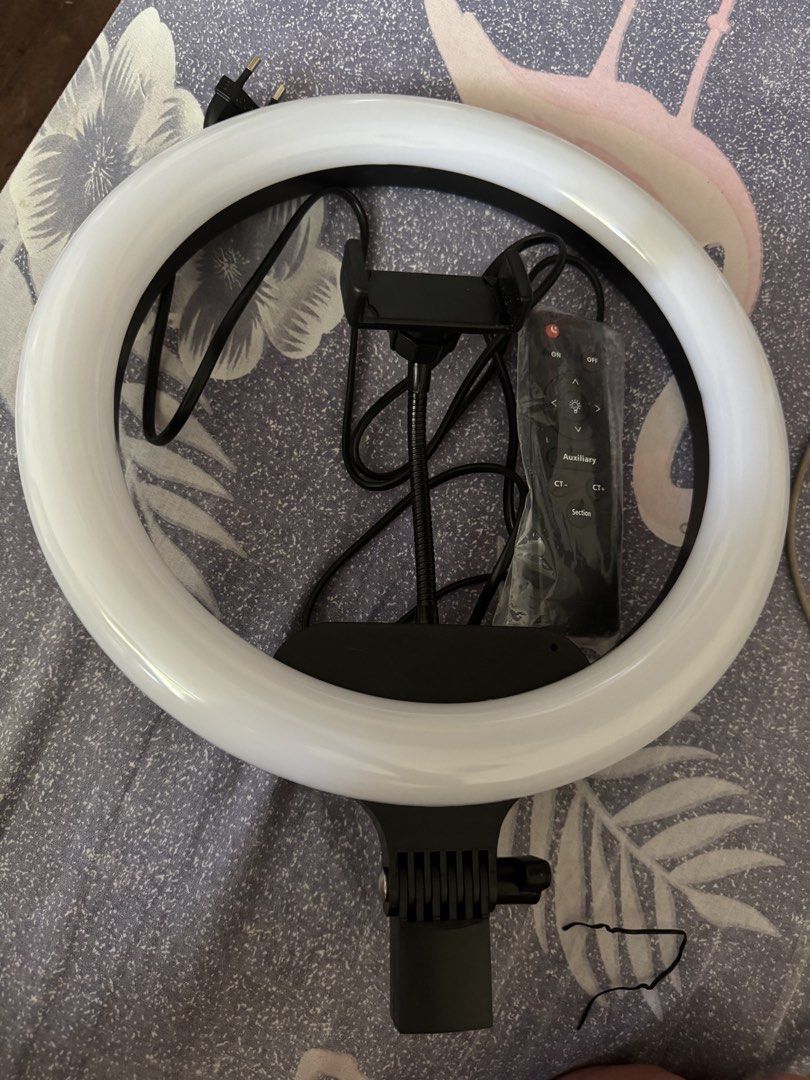 LED Ring Light with Phone Holder and Remote Control (Category: Lighting & Studio Equipment) located in Manila. Submitted by marco.21 (Listing ID 1465932326, Image 1). Description: - Black and white ring light setup in clean, fully functional condition - Includes flexible phone mount attached inside the circle - Comes with dedicated remote control still in its protective plastic wrap - Power cable equipped with a standard two-pin plug, ready to pl