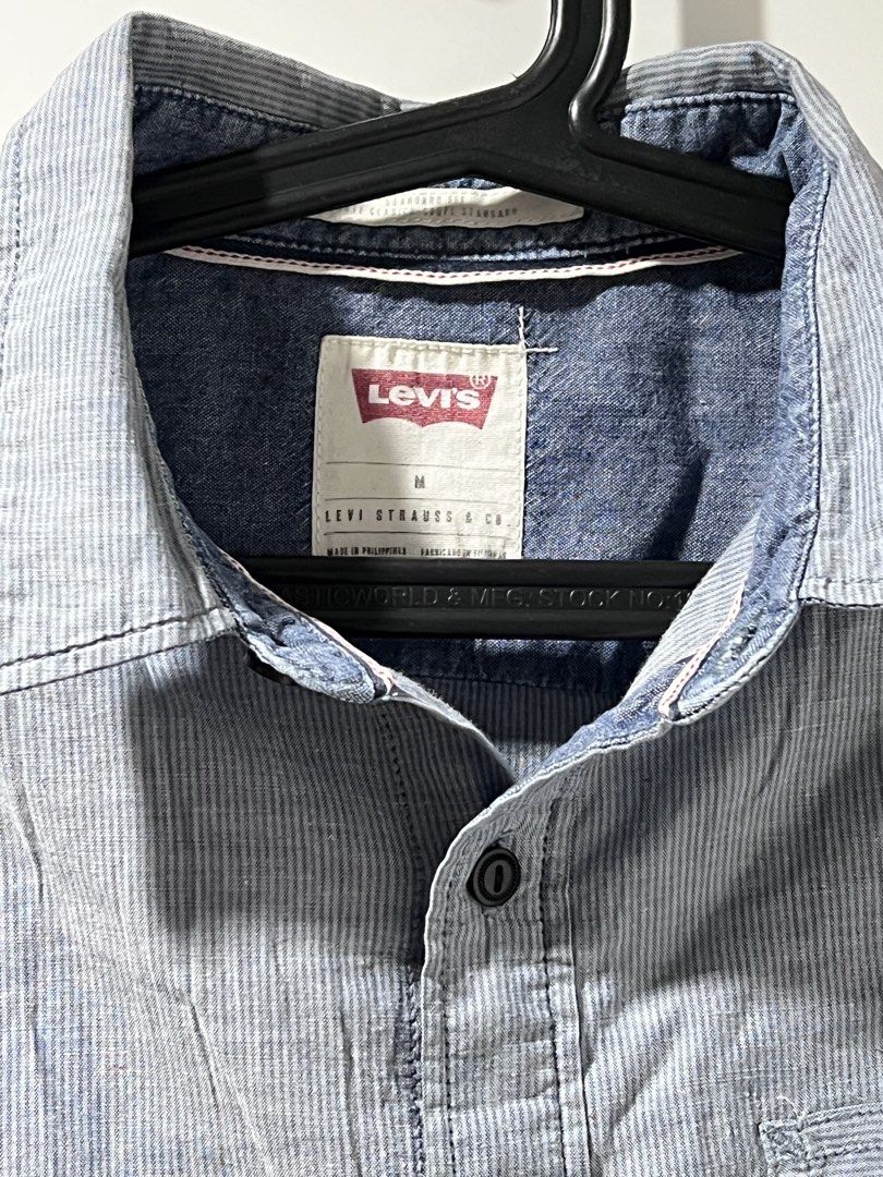 Levi's Blue Striped Long Sleeve Button-Down Shirt (Category: Tshirts & Polo Shirts ) located in Manila. Submitted by shijin_007 (Listing ID 1465836322, Image 2). Description: - Brand: Levi's - Style: Long sleeve button-down shirt - Pattern: Light blue and white stripes - Fit: Standard fit with a single left chest pocket - Details: Dark denim contrast lining on inner collar and cuffs, dark front buttons - Size: M - L: 27 inch -W: 22 inch -Minor po