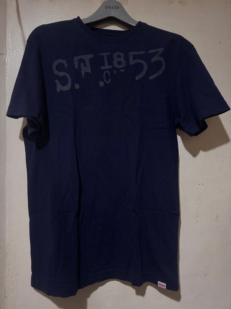 Levis Tshirt (Category: Tshirts & Polo Shirts ) located in Danao, Cebu. Submitted by welvirinec29053 (Listing ID 1465779580, Image 1). Description: This navy blue t-shirt features a faded "S.F. 1853" graphic print across the chest and a small red Levi's tag at the bottom hem. size S fit to medium dimes 19x27 color rate 9.5/10.