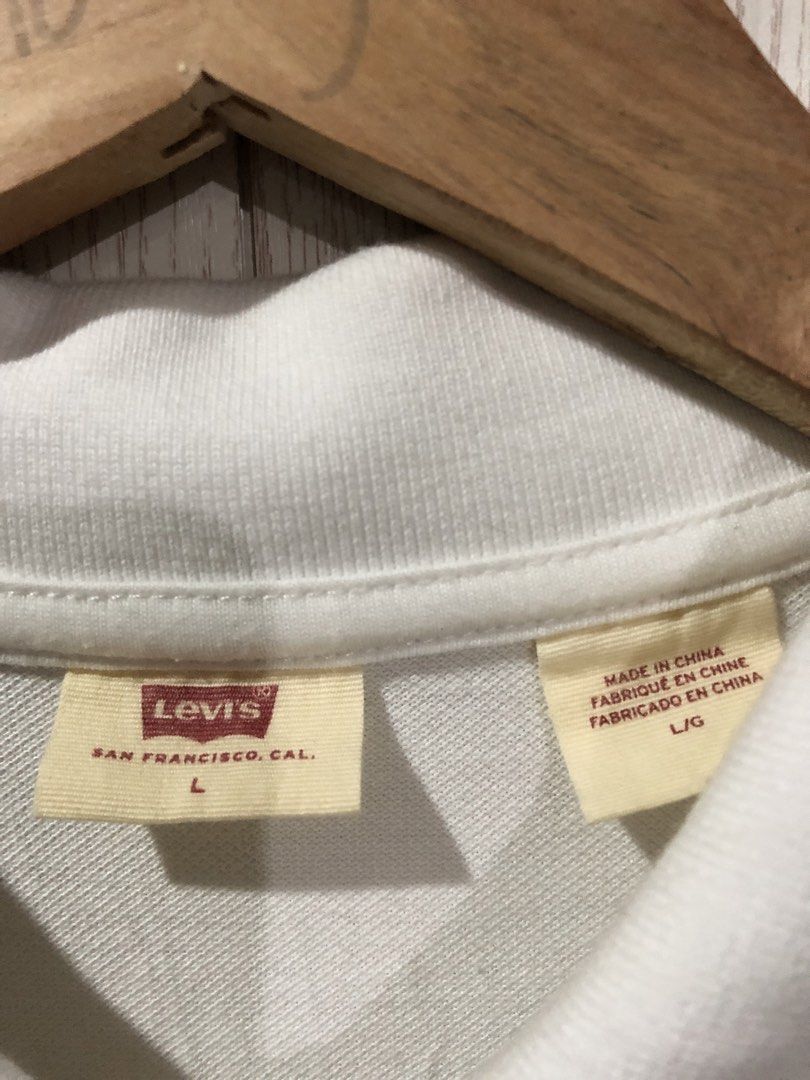 Levi's White Polo Shirt Size L (Category: Tshirts & Polo Shirts ) located in Magsaysay. Submitted by ryns_thrifting (Listing ID 1465896156, Image 2). Description: - Brand: Levi's - Color: White - Size: Large - Material: Breathable cotton pique fabric - Design: Classic three-button placket with ribbed collar and arm cuffs - Details: Embroidered red batwing logo on chest and signature red tab on lower side seam - Condition/Style: Clean look, perfec