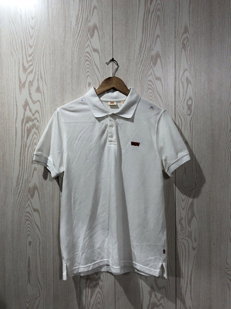 Levi's White Polo Shirt Size L (Category: Tshirts & Polo Shirts ) located in Magsaysay. Submitted by ryns_thrifting (Listing ID 1465896156, Image 1). Description: - Brand: Levi's - Color: White - Size: Large - Material: Breathable cotton pique fabric - Design: Classic three-button placket with ribbed collar and arm cuffs - Details: Embroidered red batwing logo on chest and signature red tab on lower side seam - Condition/Style: Clean look, perfec