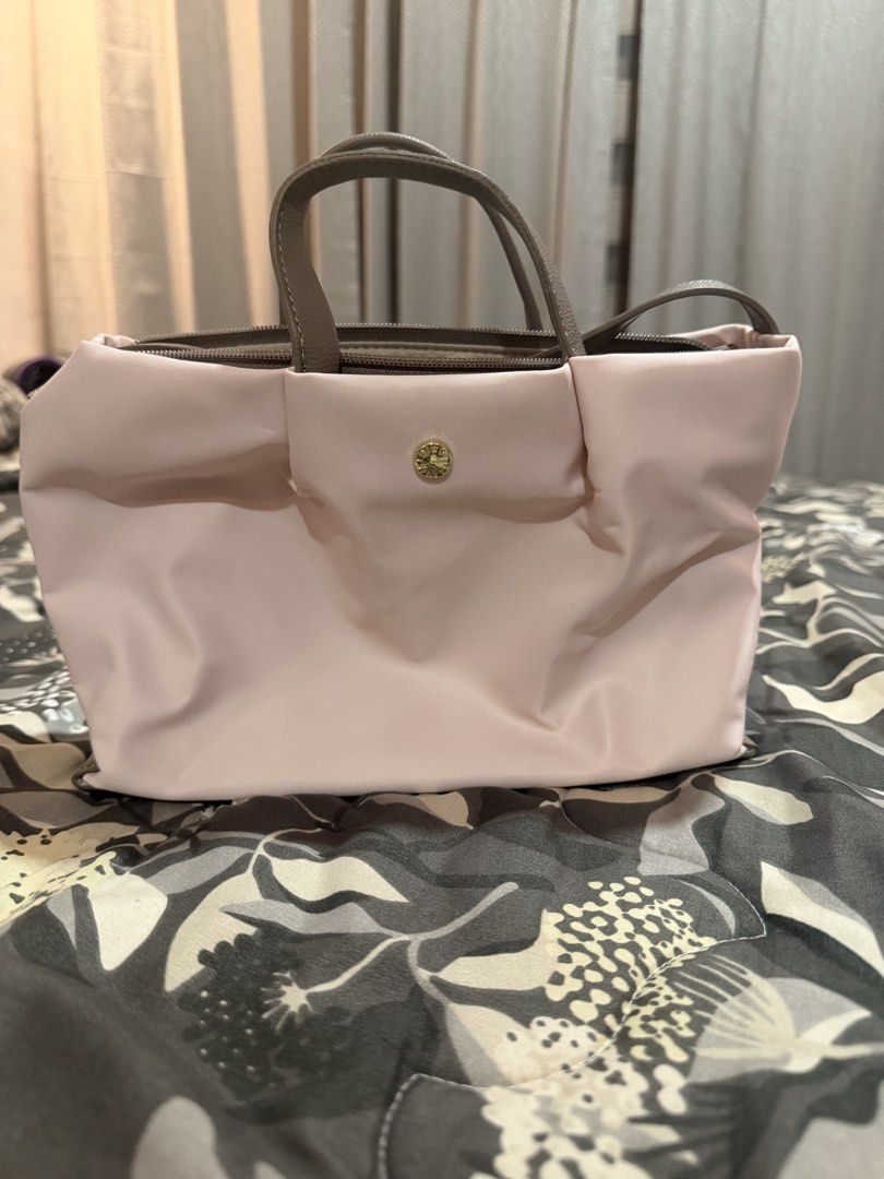 Light Pink Tote Handbag with Grey Handles (Category: Tote Bags) located in Mexico. Submitted by anythingluxe (Listing ID 1465912641, Image 1). Description: - Color: Soft pink with grey leather-look handles - Material: Smooth satin-like fabric with a structured rectangular base - Closure: Secure top zip closure - Details: Small round gold-tone metal emblem on the front flap - Interior: Clean layout with multiple compartments for easy organization 