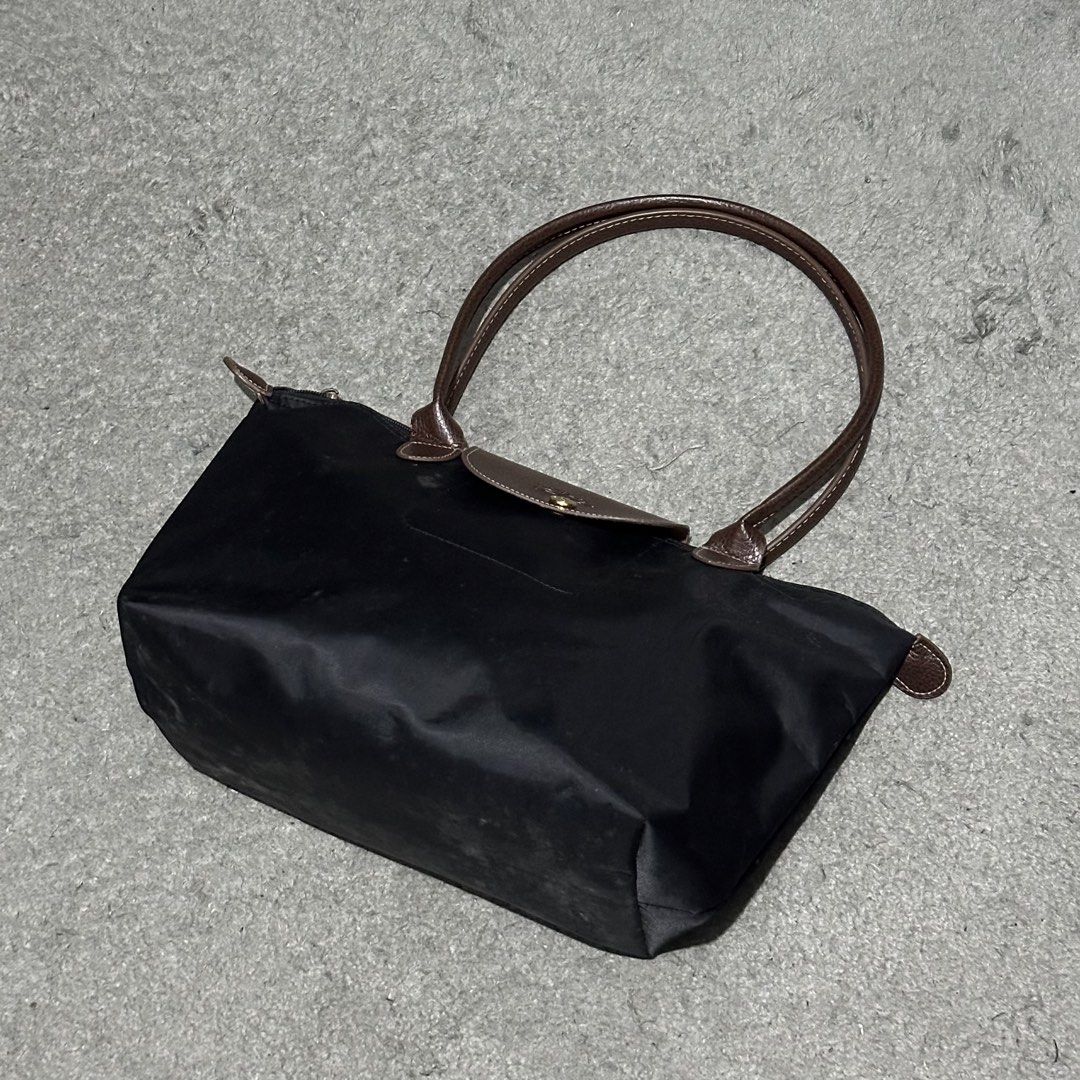 Longchamp Le Pliage Long Handle Black Tote Bag (Category: Luxury Bags & Wallets) located in Lipa City. Submitted by jecoparra (Listing ID 1465837214, Image 2). Description: - Brand: Longchamp Le Pliage - Color: Classic black with brown leather handles and flap closure - Hardware: Gold-tone hardware on the snap button - Closure: Secure zip top with snap flap - Features: Comfortable long shoulder straps, lightweight and spacious - Perfect for: Work