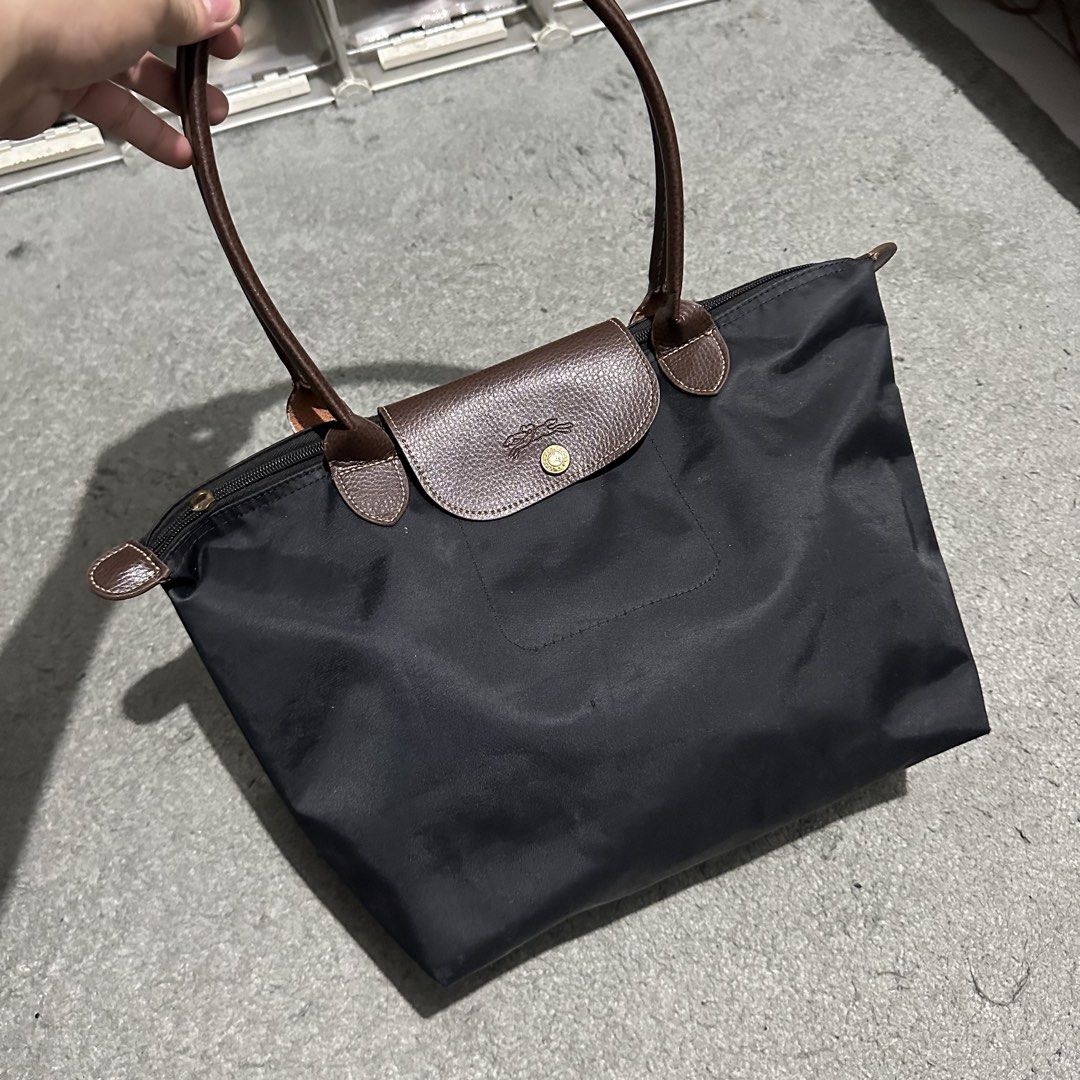 Longchamp Le Pliage Long Handle Black Tote Bag (Category: Luxury Bags & Wallets) located in Lipa City. Submitted by jecoparra (Listing ID 1465837214, Image 3). Description: - Brand: Longchamp Le Pliage - Color: Classic black with brown leather handles and flap closure - Hardware: Gold-tone hardware on the snap button - Closure: Secure zip top with snap flap - Features: Comfortable long shoulder straps, lightweight and spacious - Perfect for: Work