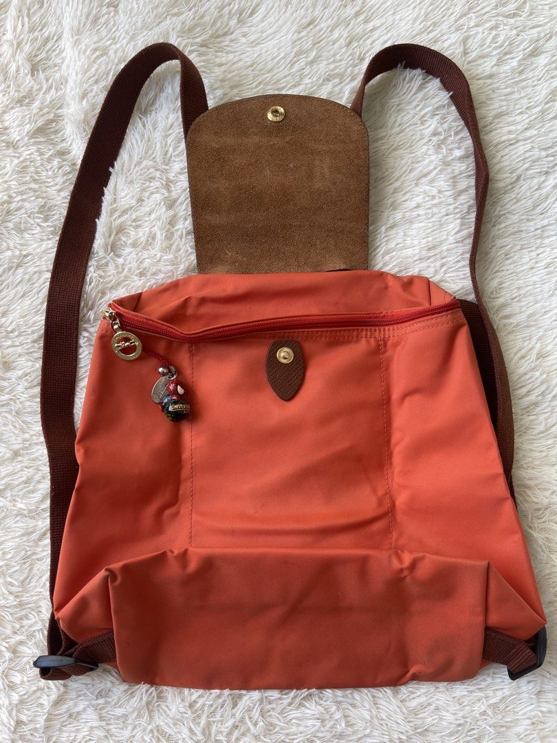 Longchamp Le Pliage Orange Nylon Backpack (Category: Backpacks) located in Malolos. Submitted by ishnnt (Listing ID 1465907929, Image 1). Description: - Brand: Longchamp - Color: Vibrant Orange with Brown Leather flap and straps - Material: Durable, easy-to-clean nylon with gold-tone hardware - Design: Lightweight, foldable, and packs completely flat - Inclusion: Comes with an adorable Spider-Man zipper charm - Flaws: Minor dirt marks/stains near