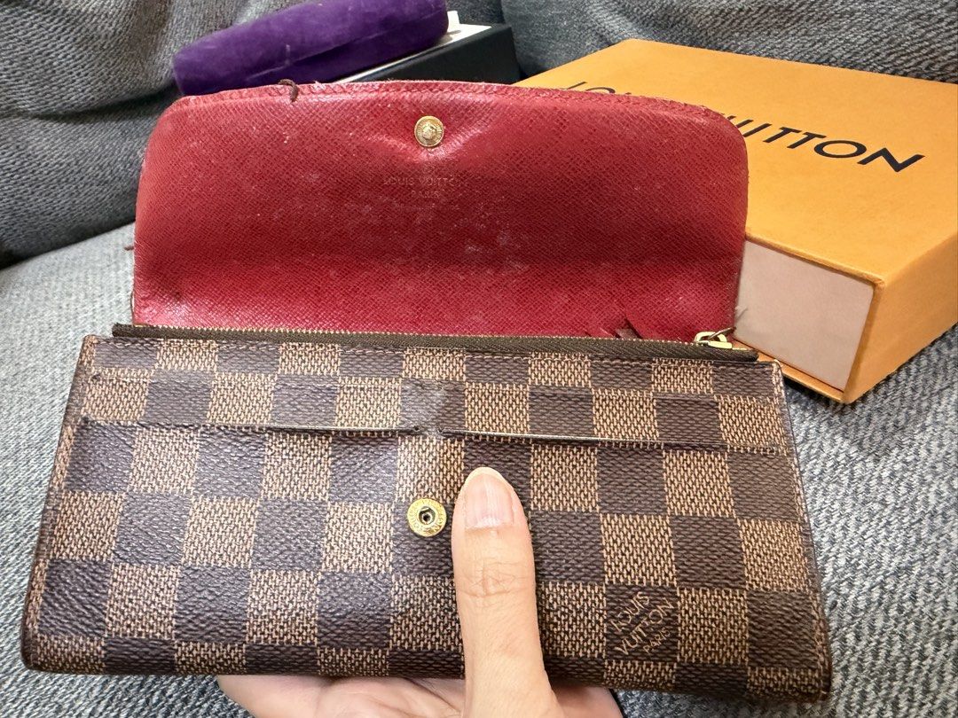 Louis Vuitton Damier Ebene Long Wallet (Category: Luxury Bags & Wallets) located in Las Pinas. Submitted by wackywel (Listing ID 1465770687, Image 2). Description: - Authentic Louis Vuitton Damier Ebene canvas wallet - Gold-tone hardware with secure snap closure - Red interior lining featuring multiple card slots and zippered compartments - Condition: Noticeable wear along flap edges and scuffing on the inside red lining - Inclusion: Original ora