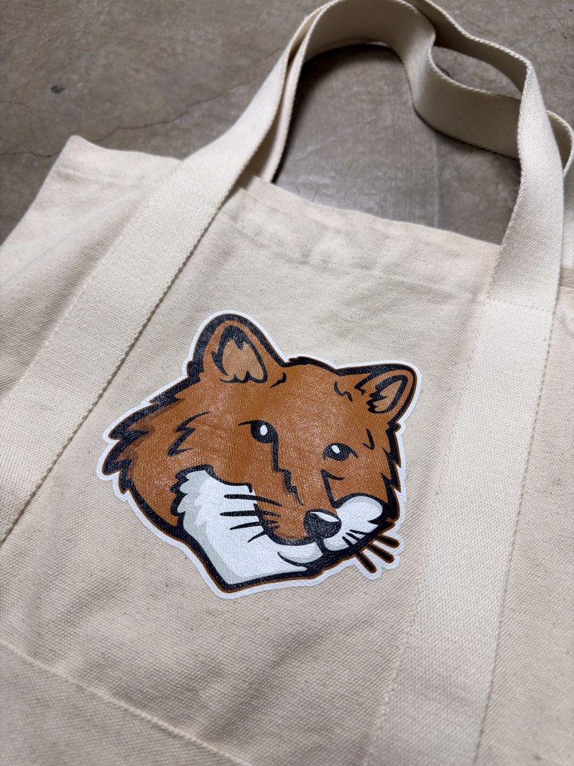 Maison Kitsune Fox Canvas Tote Bag (Category: Tote Bags) located in Alfonso. Submitted by jbcamet (Listing ID 1465921276, Image 2). Description: - Brand: Maison Kitsuné - Color: Off-white - Design: Large embroidered fox patch on front, cursive logo on back - Features: Sturdy double handles, open top, roomy interior, and convenient inside pocket with brand label - Condition/Usage: Great everyday carryall for daily commute, work, or classes.