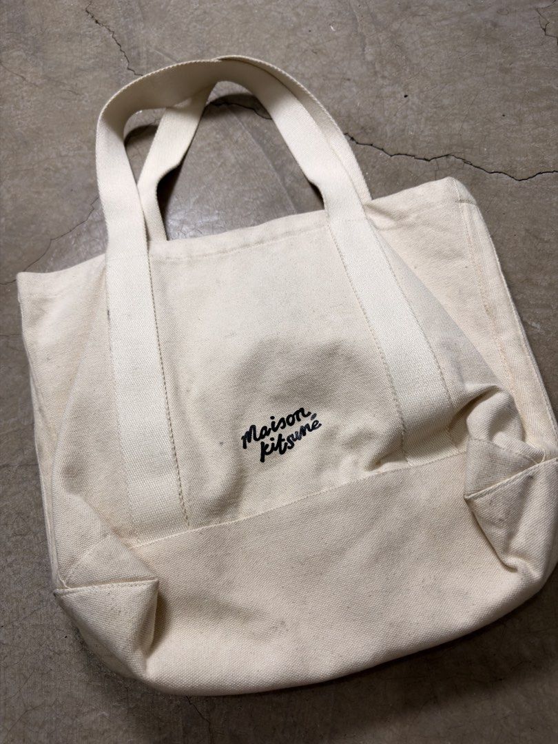 Maison Kitsune Fox Canvas Tote Bag (Category: Tote Bags) located in Alfonso. Submitted by jbcamet (Listing ID 1465921276, Image 3). Description: - Brand: Maison Kitsuné - Color: Off-white - Design: Large embroidered fox patch on front, cursive logo on back - Features: Sturdy double handles, open top, roomy interior, and convenient inside pocket with brand label - Condition/Usage: Great everyday carryall for daily commute, work, or classes.