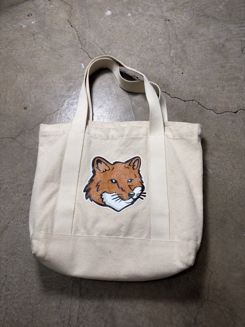 Maison Kitsune Fox Canvas Tote Bag (Category: Tote Bags) located in Alfonso. Submitted by jbcamet (Listing ID 1465921276, Image 1). Description: - Brand: Maison Kitsuné - Color: Off-white - Design: Large embroidered fox patch on front, cursive logo on back - Features: Sturdy double handles, open top, roomy interior, and convenient inside pocket with brand label - Condition/Usage: Great everyday carryall for daily commute, work, or classes.