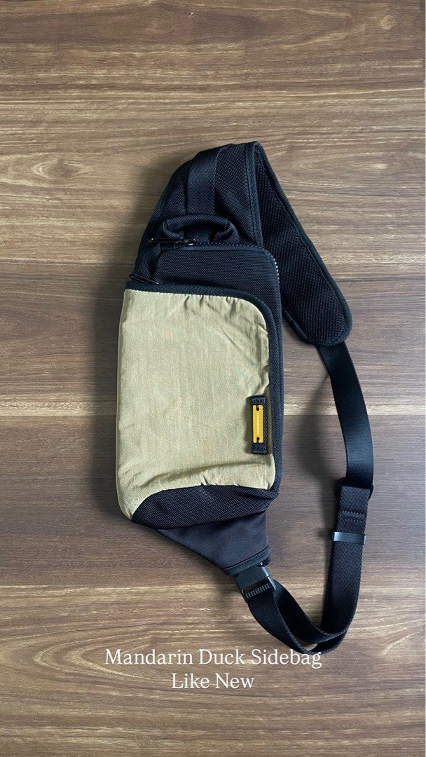 Mandarin Duck Sidebag Crossbody Bag (Category: Cross-body Bags) located in Bacolod City. Submitted by jmcercado (Listing ID 1465925714, Image 1). Description: - Brand: Mandarin Duck - Colorway: Black and olive green - Design: Single strap with breathable mesh shoulder padding and adjustable buckle closure - Storage: Small zipped top compartment and front flap pocket with yellow branding label - Build: Sturdy zippers and durable fabric constructio