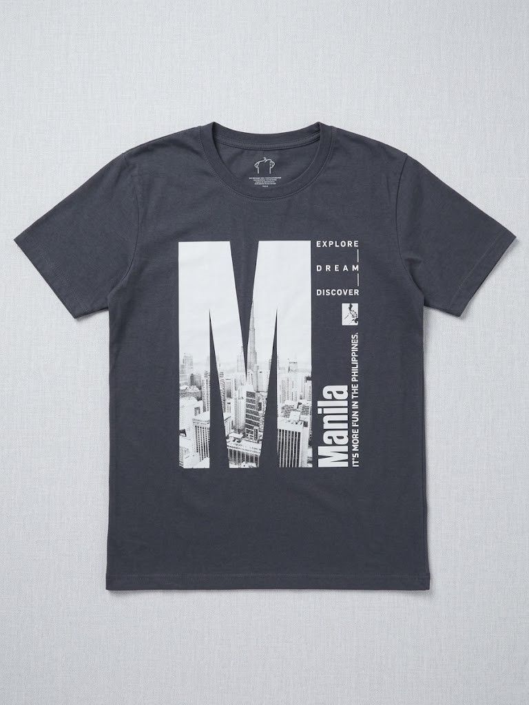 Manila Explore Dream Discover Graphic T-Shirt Grey (Category: Tshirts & Polo Shirts ) located in Pasig City. Submitted by chinchan1 (Listing ID 1465861982, Image 1). Description: - Dark grey short-sleeve graphic tee with crew neckline - Features a large white 'M' letter filled with a Manila skyline photo - Printed text: 'EXPLORE DREAM DISCOVER' and 'Manila It's More Fun In The Philippines' - Made of soft, comfortable cotton material - Clean condi