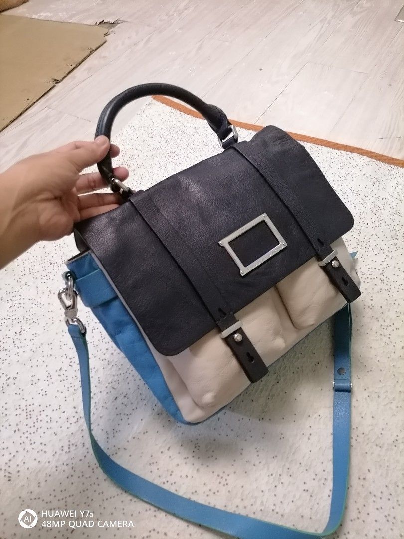Marc by Marc Jacobs Leather Satchel (Category: Luxury Bags & Wallets) located in Naga. Submitted by mrwisethrifter (Listing ID 1465827028, Image 3). Description: - Brand: Marc by Marc Jacobs - Design: Colorblock in chic black, cream, and blue - Versatile Carry: Includes a top handle and an adjustable blue shoulder strap - Secure & Stylish: Front flap closure with dual vertical straps and silver-tone metal plaque hardware - Storage: Two convenient