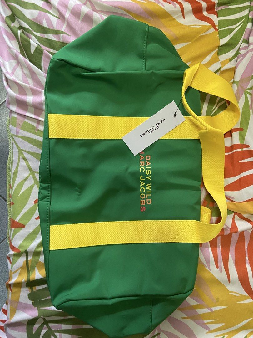 Marc Jacobs Daisy Wild Duffel Bag (Category: Luxury Bags & Wallets) located in Silang. Submitted by Apple_Mac07 (Listing ID 1465826216, Image 1). Description: Green canvas duffel bag with bright yellow handles. Front printed with Daisy Wild Marc Jacobs lettering in pink and orange. Pink zipper features a flower-shaped pull tag. Inside lined with vibrant orange and red fabric. Brand new with tag attached..