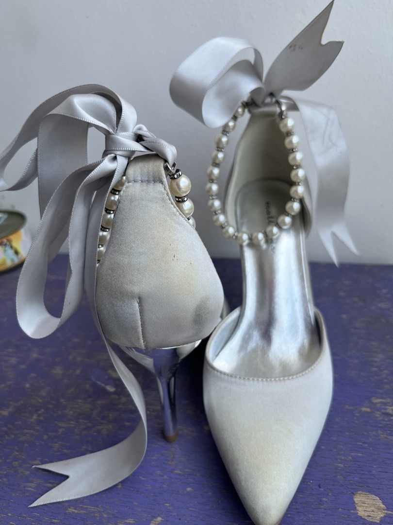 Matthews (Category: Heels) located in Quezon City. Submitted by albie.mari (Listing ID 1465778239, Image 3). Description: Elegant pointed-toe heels with beautiful pearl accents and oversized satin ribbon details. Perfect for weddings, debuts, formal events, bridal shoots, or special occasions. Condition: Pre-loved Color: White/Silver Details: Pearl embellishments + satin ribbon ankle ties ⚠️ Please note: There is a light yellowish stain/discolora